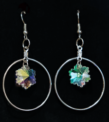 Pair of silver-colored earrings with reflective charms. 